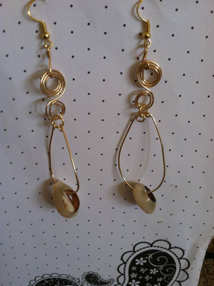 Gold cowry shell hoop style earrings with swirls.