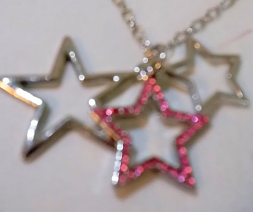 Silver necklace with 3 star shaped silver-tone accents with pink crystals. 18 inch chain