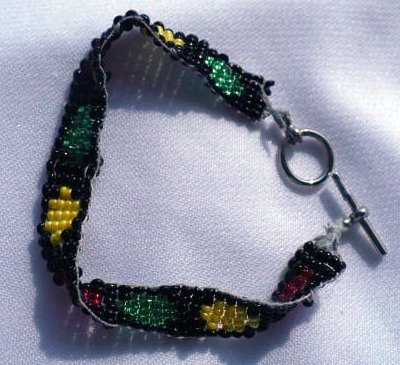 Bracelet with red yellow and green circles on a black background made of seed beads.