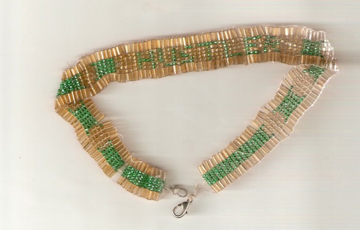 Necklace woven with green and gold seed beads and bugle beads spells out the word hustler