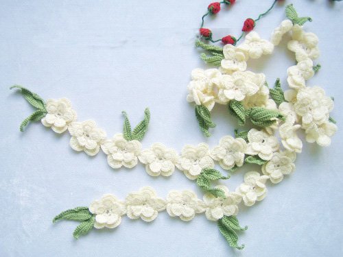 Hand-crochetted white peachblossom flowers scar f with green leaves