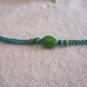 Green stone with wood beads on blue square