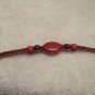 Red stone with wood beads on black and red square