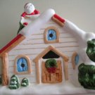 CHRISTMAS  HOUSE W/CANDLE & SANTA ON SNOW COVERED ROOF