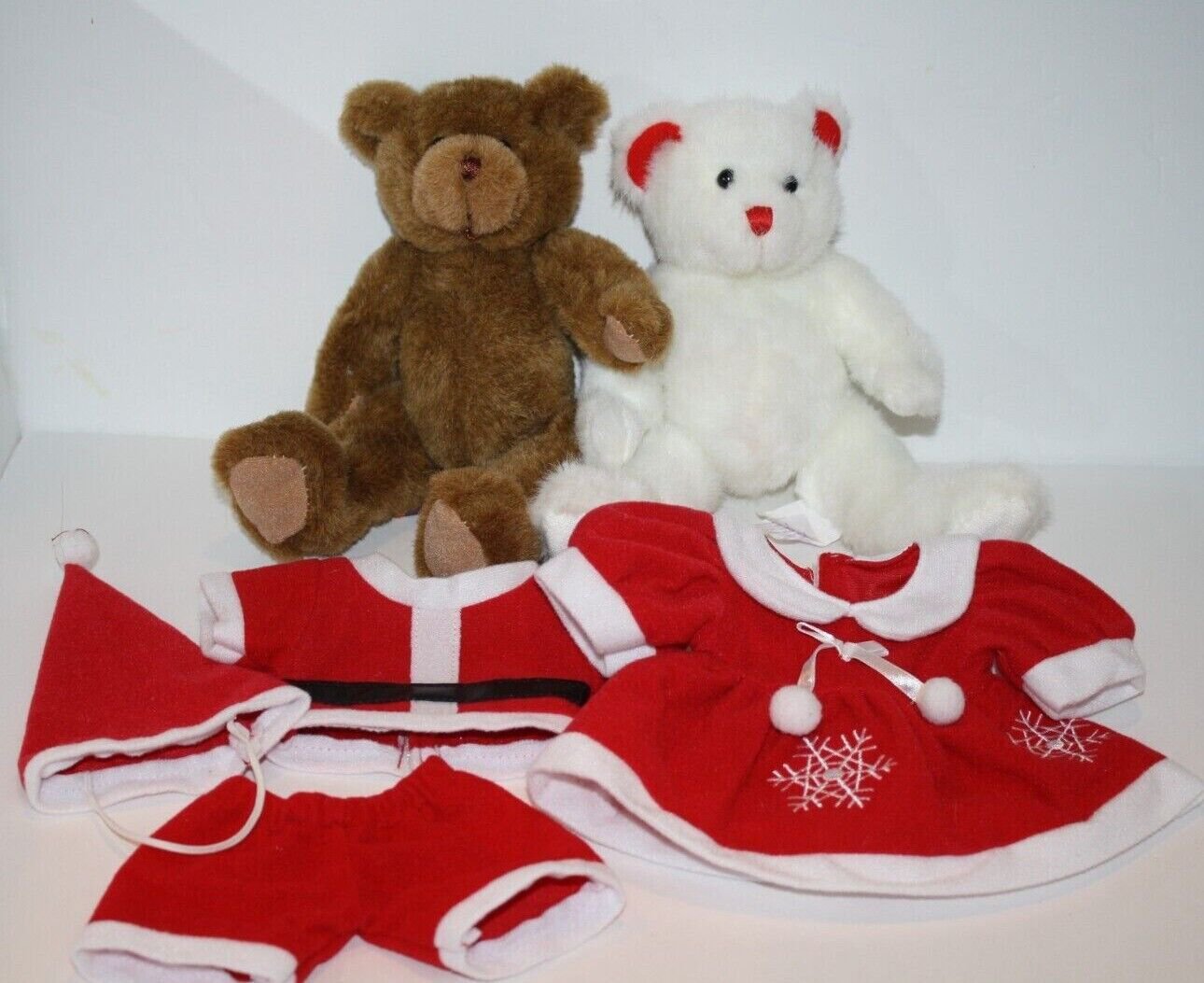A teddy bear dressed in a santa outfit next to a christmas tree