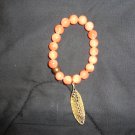 Pretty orange bracelet with big statement gold charm
