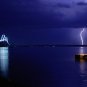 Awesome Lightning Photo over Water with Lighted Bridge Night Sky Poster