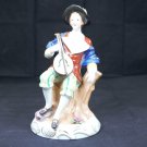 Made in Occupied Japan figurine man holding an instrument sitting on tree stump