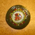 Large colorful metal button with feathers.