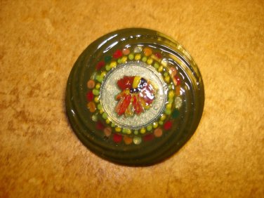 Large colorful metal button with feathers.