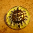Large metal button with smiling sun.