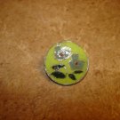 Signed silver metal button with green flower.