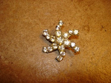 Silver metal button in shape of snowflake with white rhinestones.