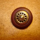 Brown plastic button with gold metal wheel.
