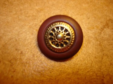 Brown plastic button with gold metal wheel.