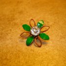 Metal button in shape of flower with white rhinestone.