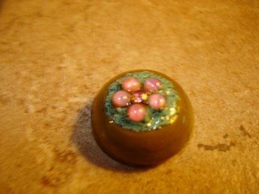 Dome shape plastic button with pink rhinestones and metal back.