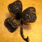 Large clover like metal button with black stone.