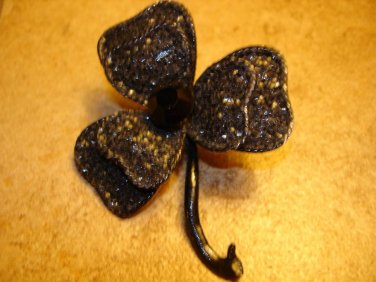 Large clover like metal button with black stone.