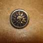 Silver metal button with blazing sun.