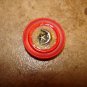 Red plastic button with silver metal moon and star.