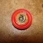 Red plastic button with silver metal moon and star.