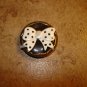 Large gold metal button with large bow.