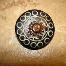 Carved black plastic button with brass sun. Carved black plastic button with brass sun.