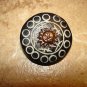 Carved black plastic button with brass sun.