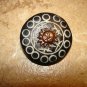 Carved black plastic button with brass sun.