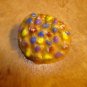 Large plastic button with painted colorful dots.