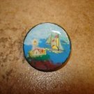 Large painted plastic button with lighthouse and sailboat.
