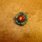 Small red and green metalized plastic button.