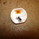 Mother of pearl button with red sun and figure.