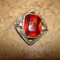 Silver metal button with large garnet color stone.