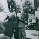 Actors help sandbag theater; Rex Harrison handing down from a lorry to Miss Dian