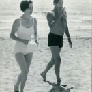 Robert Mitchum at beach with woman. - 8x10 photo