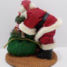 Santa Claus with Christmas bag of toys in front of fireplace Figurine