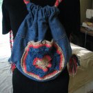 Upcycled and Reconstructed Jean Drawstring Bag With a Bright Crocheted pocket front.
