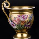 Decor Art. Porcelain Gold Cup with flowers on the gold background.