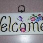 welcome sign with small burgundy & purple flowers