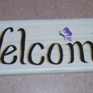 welcome sign with blue & small orange flowers